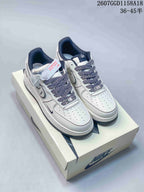 Pair of white low-top sneakers with patterned laces and dark lining displayed on a light shoebox.