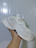 Angled view of the all-white sneaker highlighting the mesh upper, layered side panels, lace fastening, and raised sole.