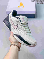 White and dark navy Nike JA 2 basketball shoe with a pale pink Swoosh.