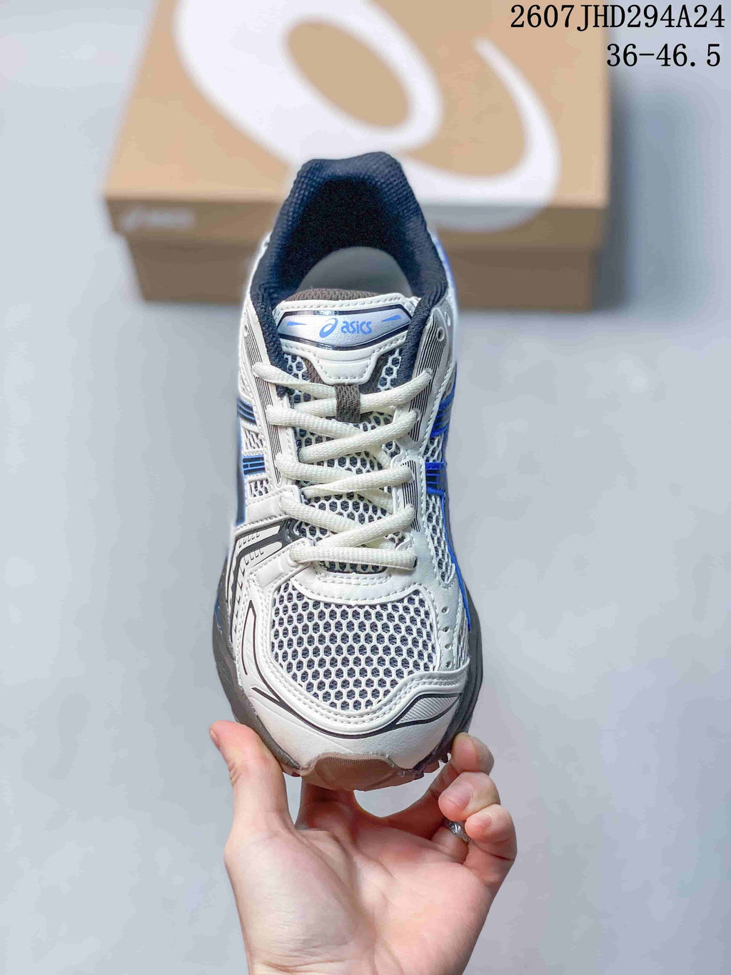 Top view of the ASICS sneaker showing the white laces, mesh-style toe box, tongue branding, and blue-gray detailing.