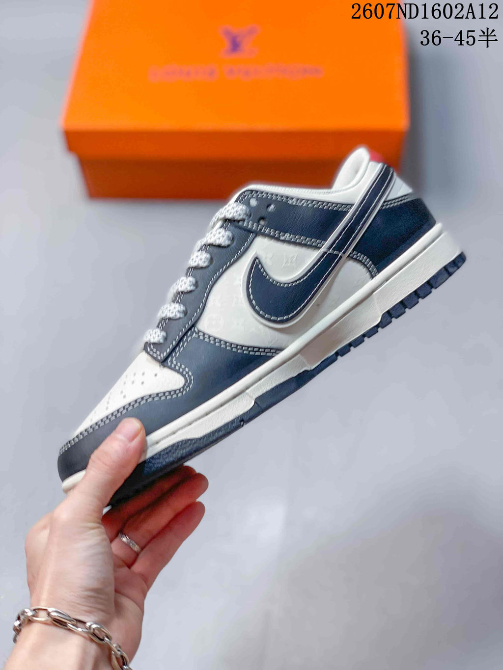 Side profile of the sneaker showing dark and white overlays, a contrasting swoosh-shaped panel, stitched edges and a layered sole.