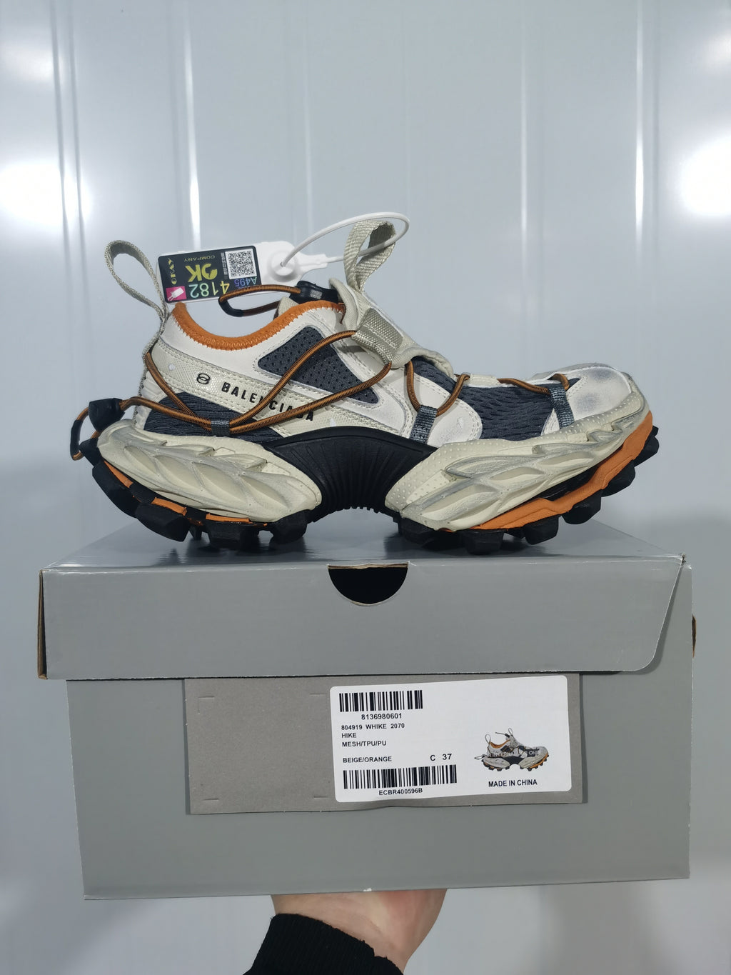Balenciaga 2070 sneakers displayed on a shoebox; the box label shows model code 2070, color text “BEIGE/ORANGE,” and size 37.