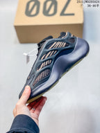 Side profile of a black sneaker with tan patterned inserts, sculpted overlays, and a pale yellow-green outsole edge.