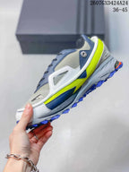 Side view highlighting the layered gray and navy upper, white structural overlays, neon yellow midsole accent and blue outsole.