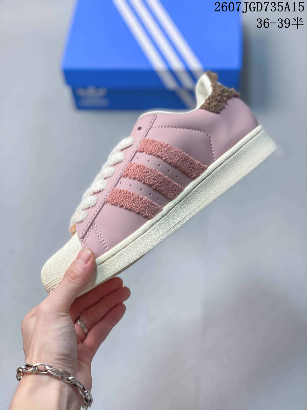Side view of a pink low-top sneaker showing the textured three-stripe details, shell toe and cream sole.