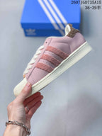 Side view of a pink low-top sneaker showing the textured three-stripe details, shell toe and cream sole.