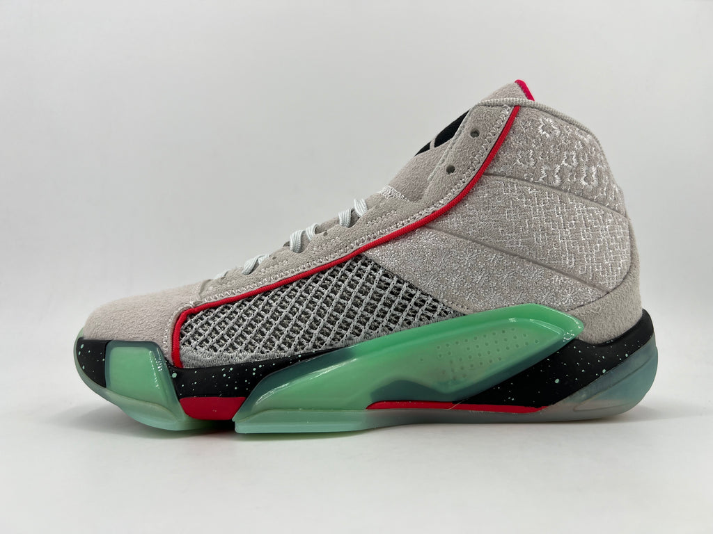 Side view of a grey Jordan Luka 1-style high-top basketball shoe with green sole accents, red trim, and a black speckled midsole.
