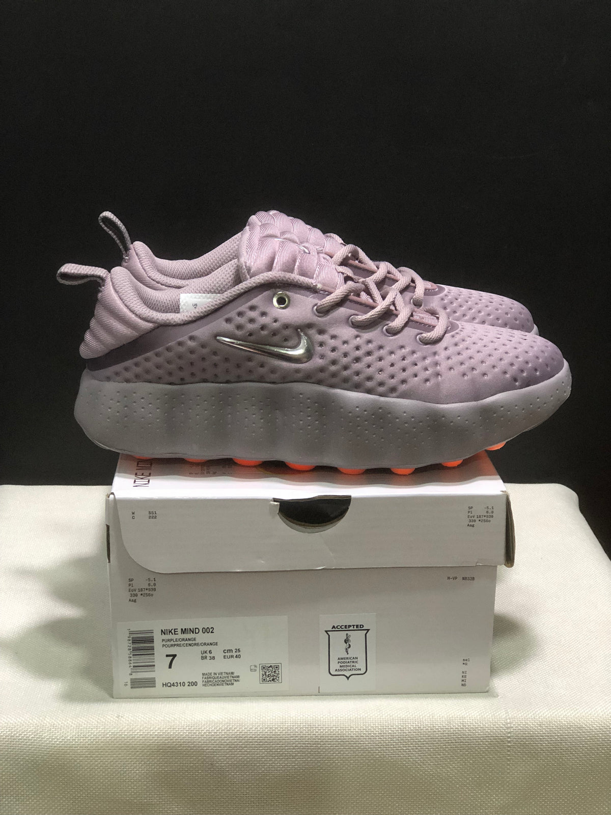 Side view of purple Nike Mind 002 sneakers with perforated uppers and sculpted soles.
