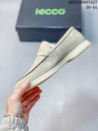 Side profile of a light beige slip-on loafer showing the apron toe, penny strap, stitching, and flat sole.