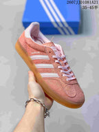 Angled side view of the pink Gazelle sneaker with visible Gazelle branding and white stripes.