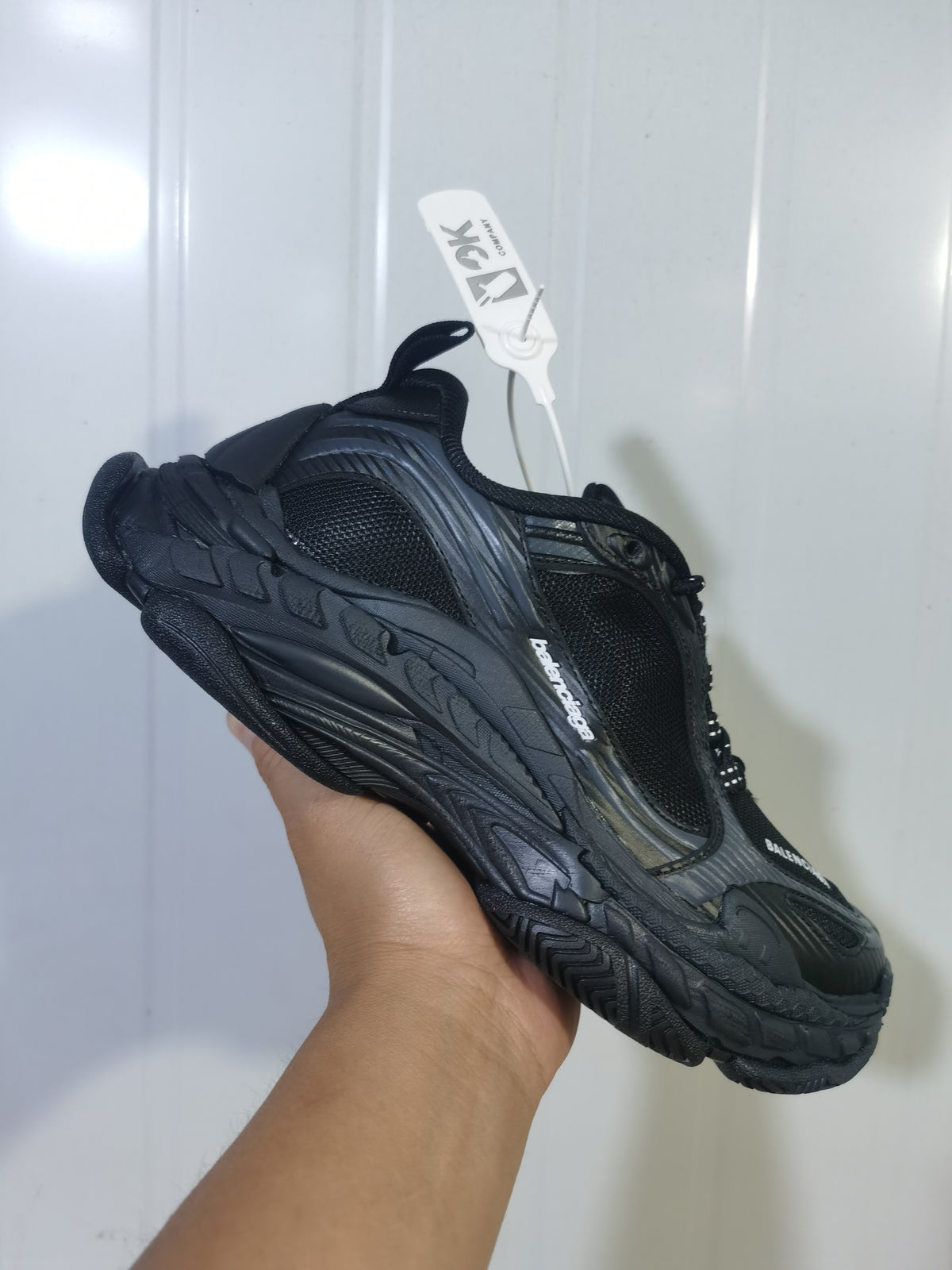 Rear three-quarter view of a black and dark grey Balenciaga Triple S 2 sneaker showing the layered heel and textured outsole.