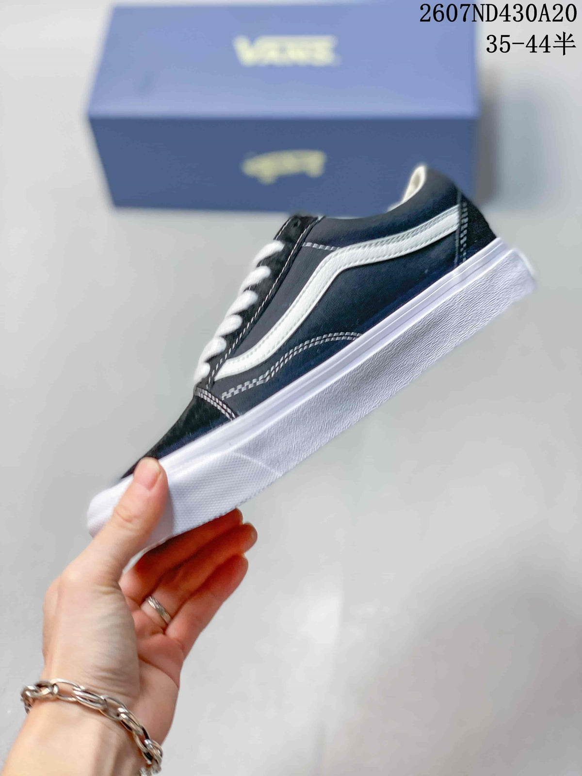 Side profile showing the black upper, contrasting white side stripe, stitching, and white rubber sole.