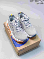 Pair of light gray ASICS GEL-NIMBUS 26 running sneakers displayed on an ASICS shoebox, with orange and dark blue outsole accents.