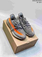 Pair of grey Adidas Yeezy Boost 350 sneakers with orange side stripes displayed on a Yeezy Boost shoe box.