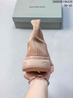 Rear view of the beige knit sneaker showing the ribbed ankle opening, heel branding, and segmented outsole.