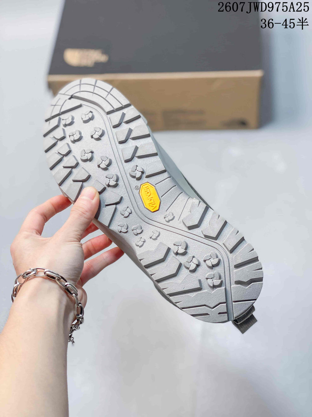 Close-up of the gray sneaker outsole showing a Vibram logo and deep lugged traction pattern.