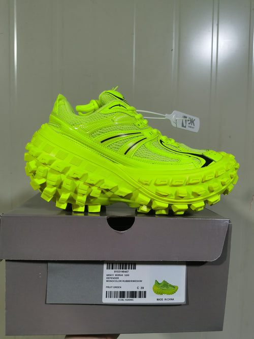 Side view of the bright green sneaker resting on its box, with a visible label identifying the color as Fruit Green and the materials as rubber and mesh.