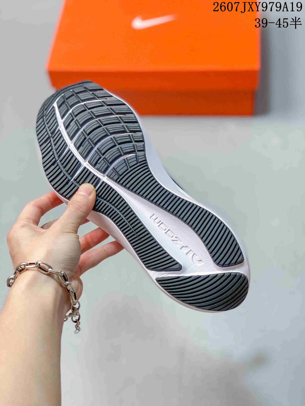 Close-up of the black patterned outsole and white midsole of the running shoe.