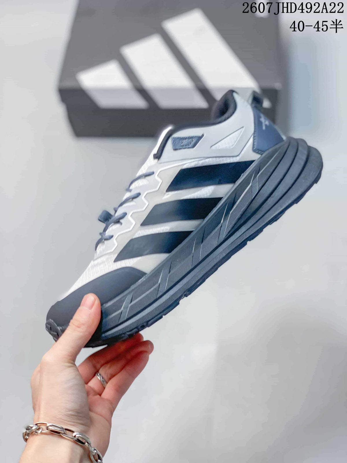 Side profile showing the white and gray upper, black overlays, lace system and thick black sole.