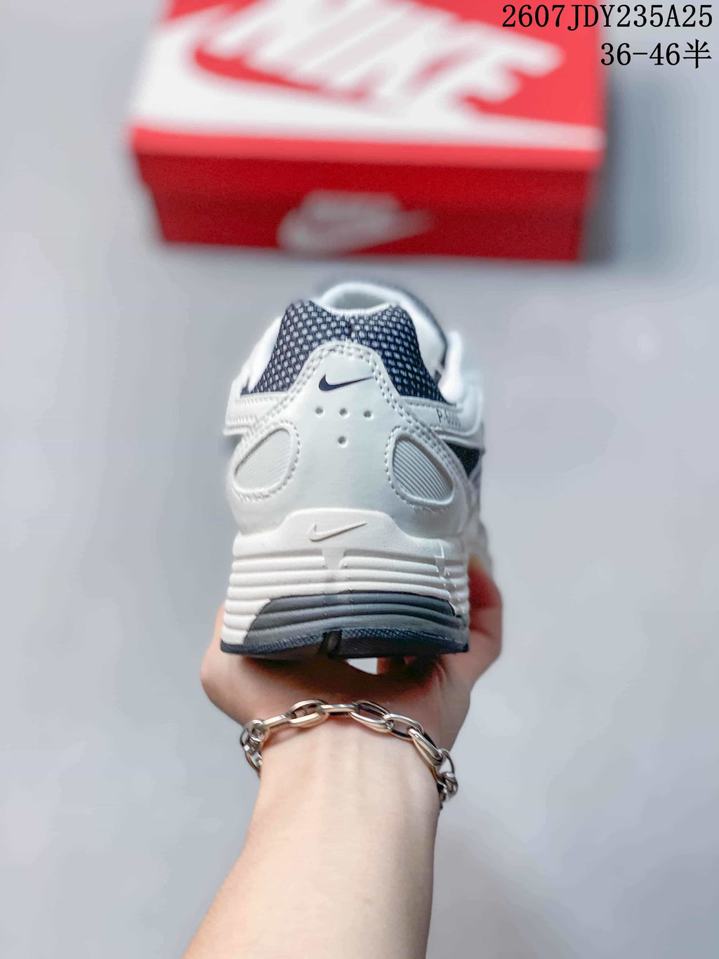 Rear view of the white and dark navy sneaker showing the padded heel, layered panels and dark outsole.