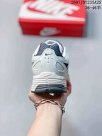 Rear view of the white and dark navy sneaker showing the padded heel, layered panels and dark outsole.