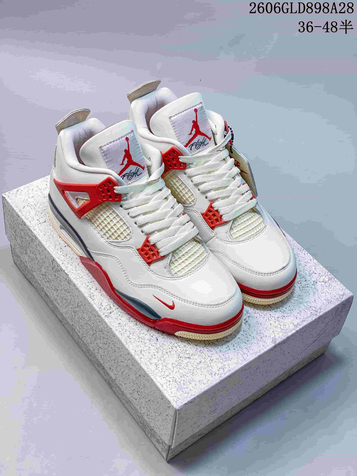 Pair of white Jordan 4 Retro mid-top sneakers with red and grey accents, shown from the front.
