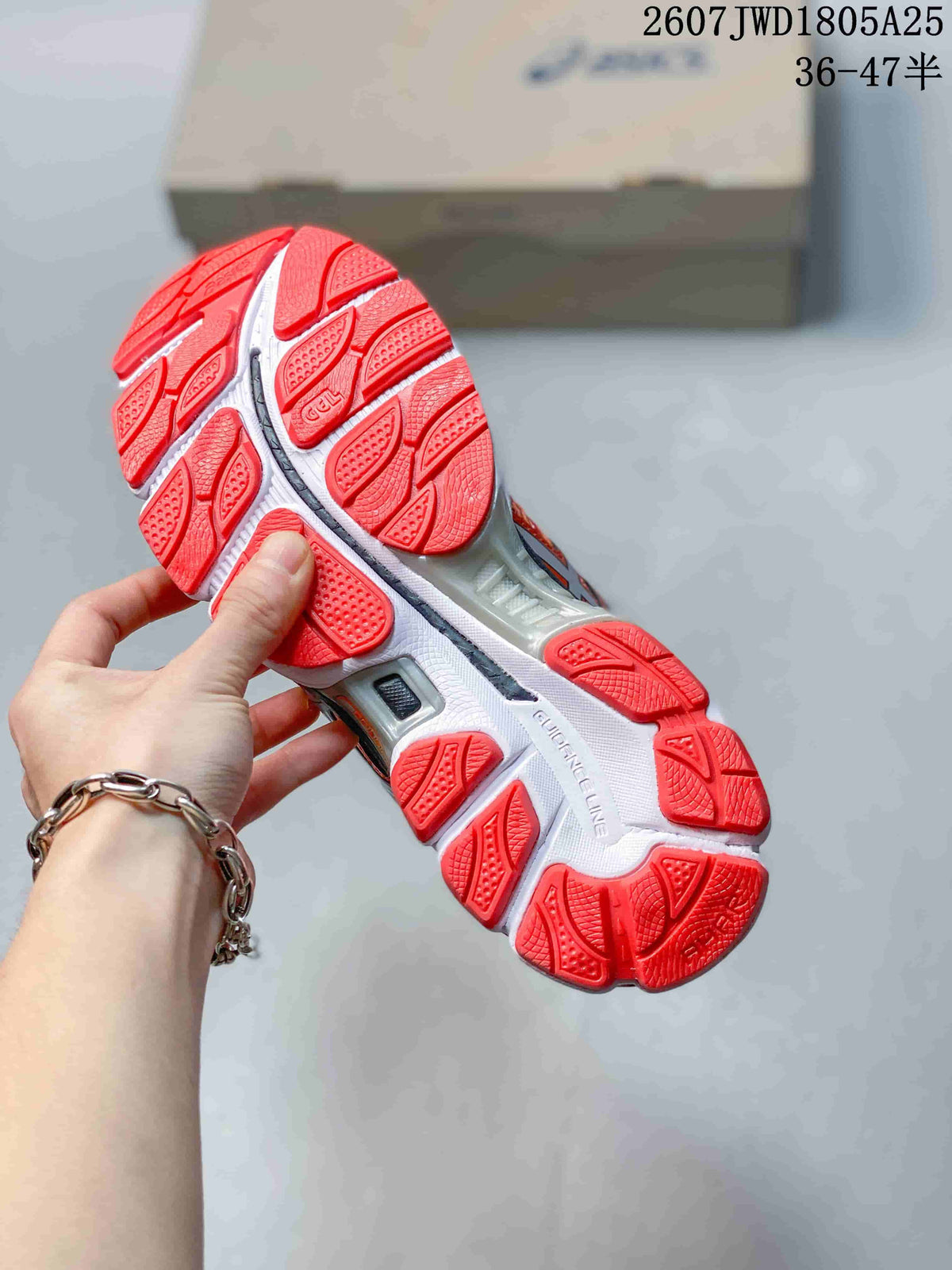 Close view of the red segmented outsole and white midsole of an ASICS running shoe.