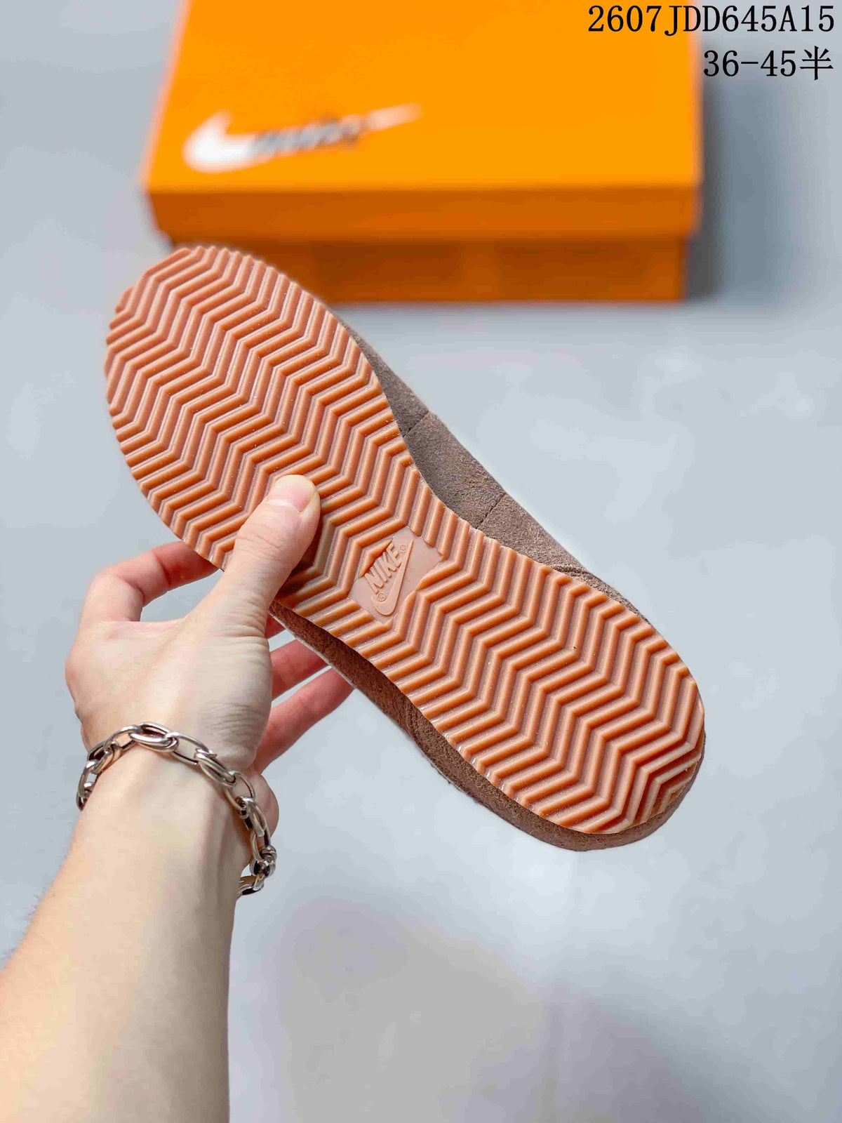 Close view of the gum-colored outsole with a repeating zigzag tread pattern and an orange Nike shoebox in the background.