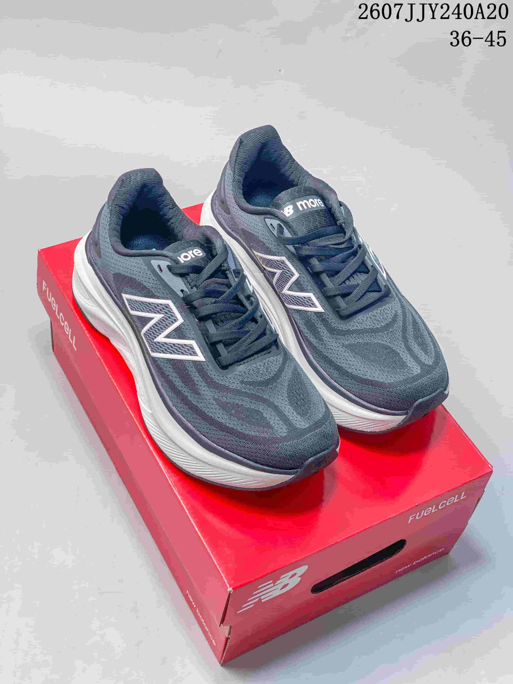 Pair of dark gray New Balance Fresh Foam X More v6 running shoes displayed on a red shoebox, with white midsoles and visible size range text.