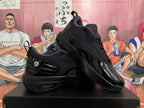 Angled view of two black Jordan sneakers displaying the textured upper, glossy overlays, pull tabs, and layered outsole.