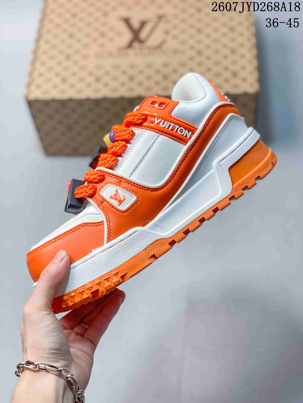 Side view showing the white and orange upper, orange laces, layered panels and textured outsole.