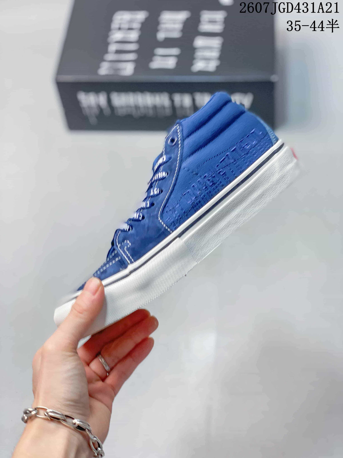 Side view of the blue sneaker showing the tonal textile-style upper, panel construction, and white rubber sole.
