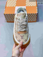 Front view of a beige monogram-patterned sneaker with white laces and a gum-colored toe bumper.