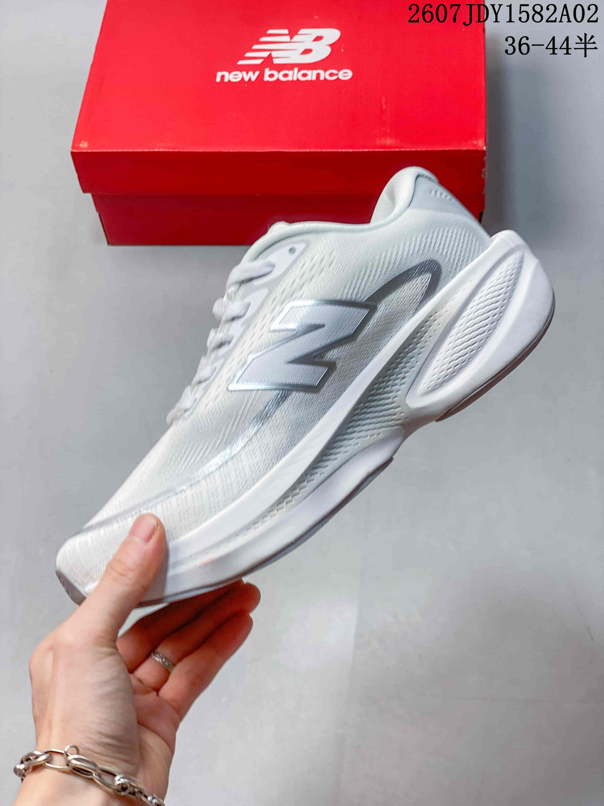 Side view of a white New Balance running shoe with a large silver logo and sculpted midsole.
