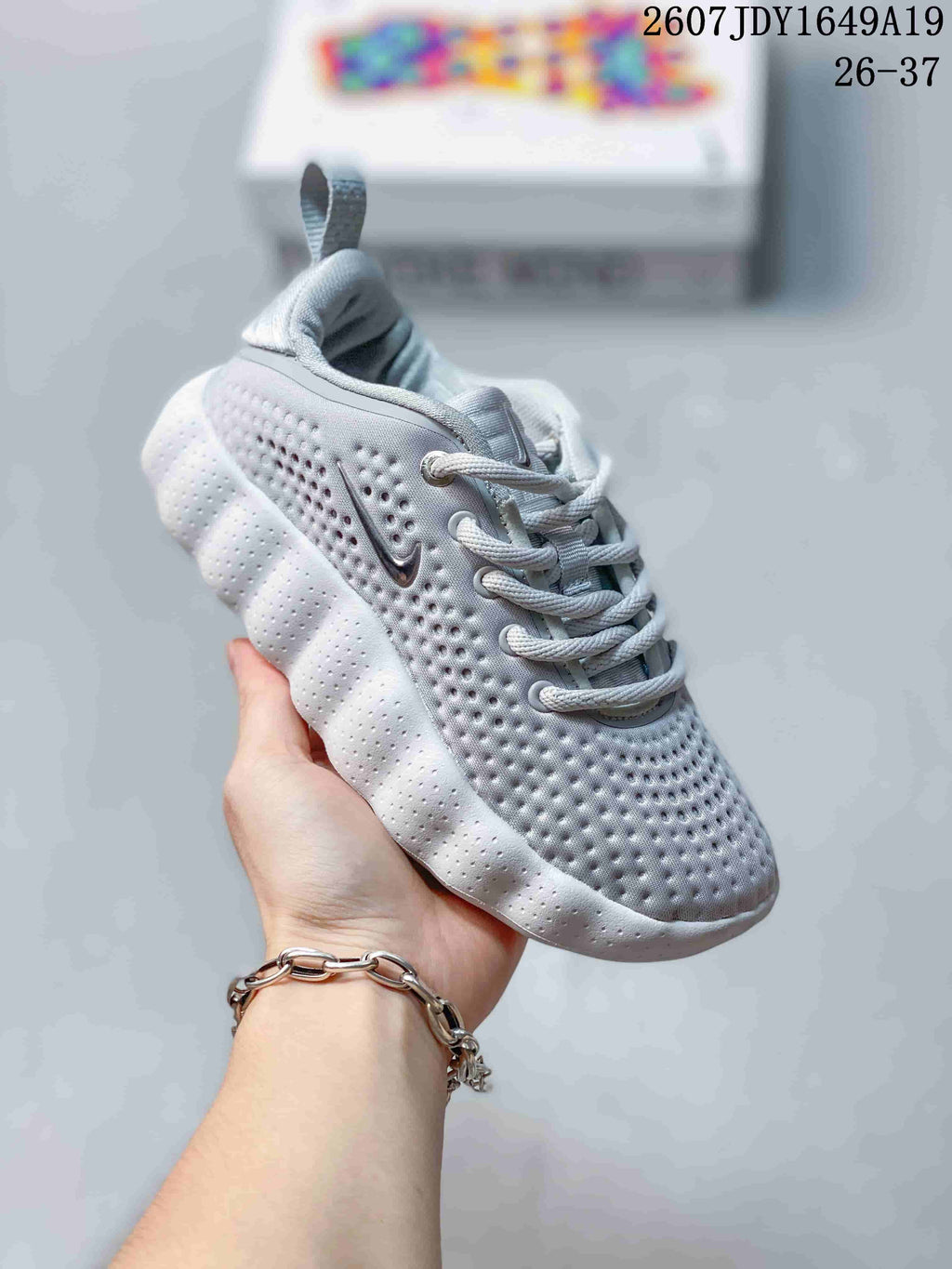 Light gray Nike Mind 002 kids sneaker with a perforated upper and pull tab.