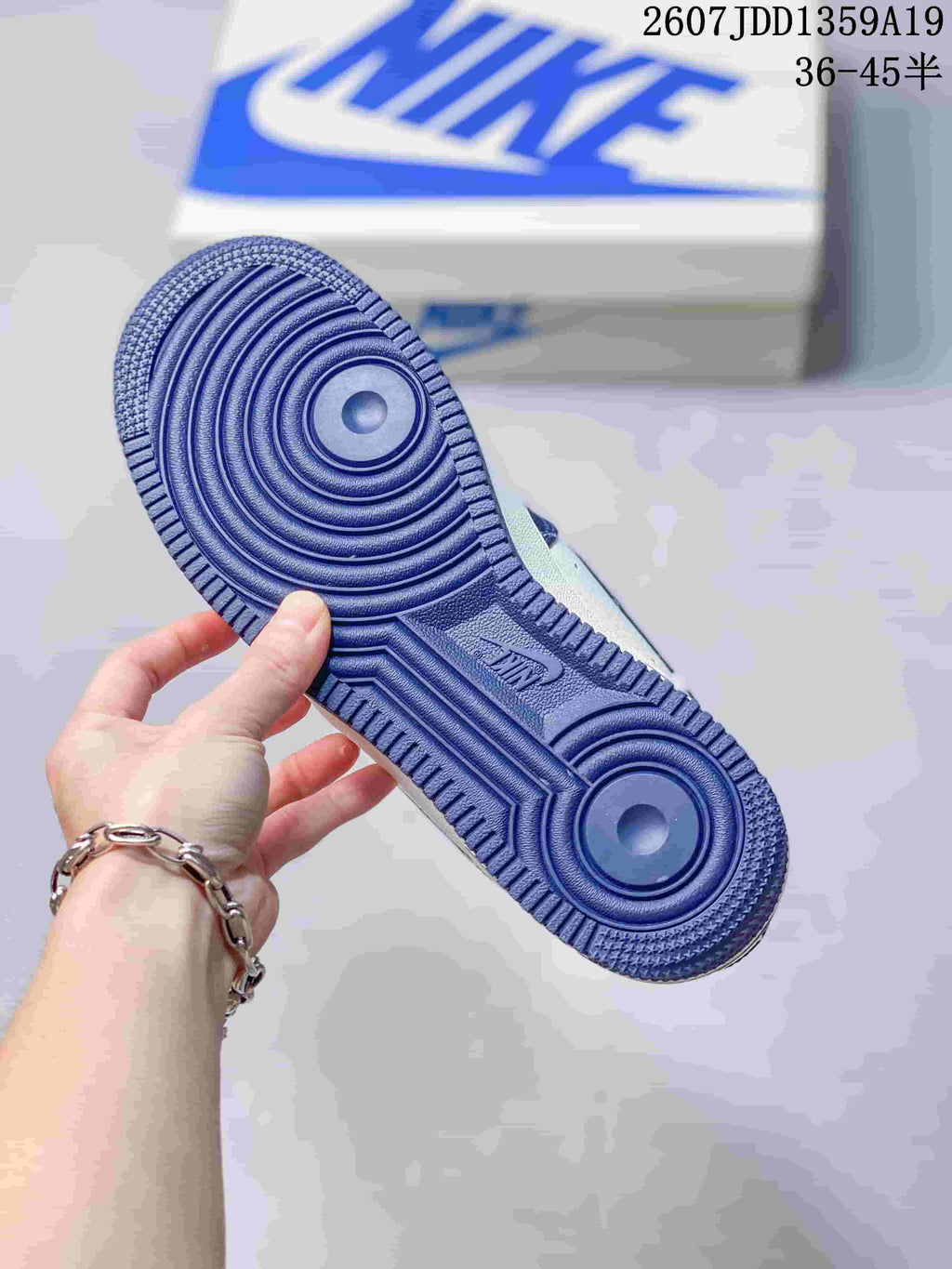 Bottom view of a sneaker showing a blue rubber outsole with concentric circular traction patterns and molded branding.