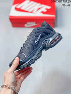 Side profile of a black Nike Air Max Plus TN sneaker showing layered panels, side logo, and visible Air cushioning details.