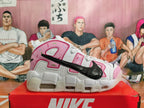 Side view showing oversized lettering, black Swoosh, pink panels, and chunky sole.