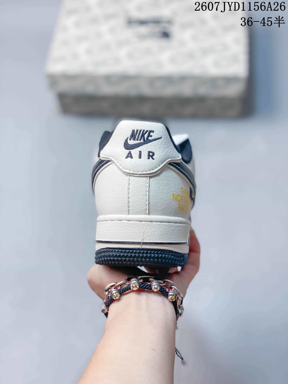 Rear view of a white and navy Nike Air Force 1 sneaker showing the Nike Air heel tab and yellow side lettering.