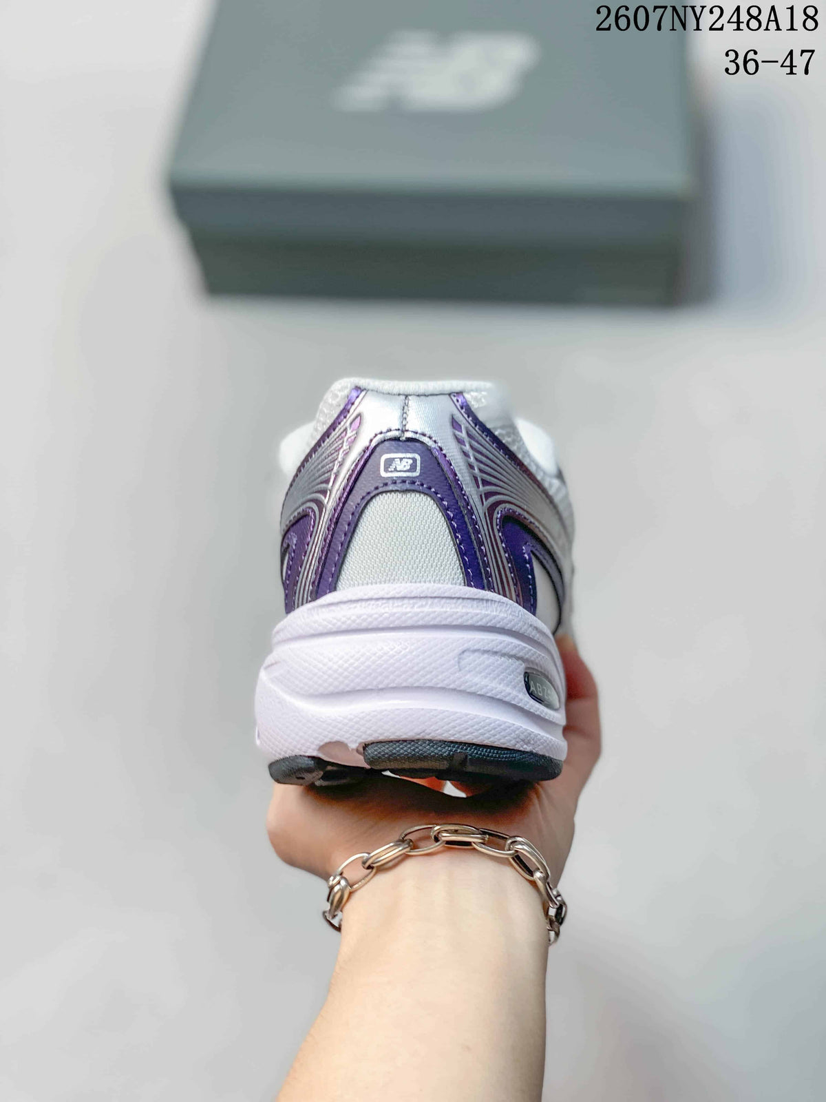 Rear view of the white and purple New Balance sneaker showing the padded heel and layered sole.