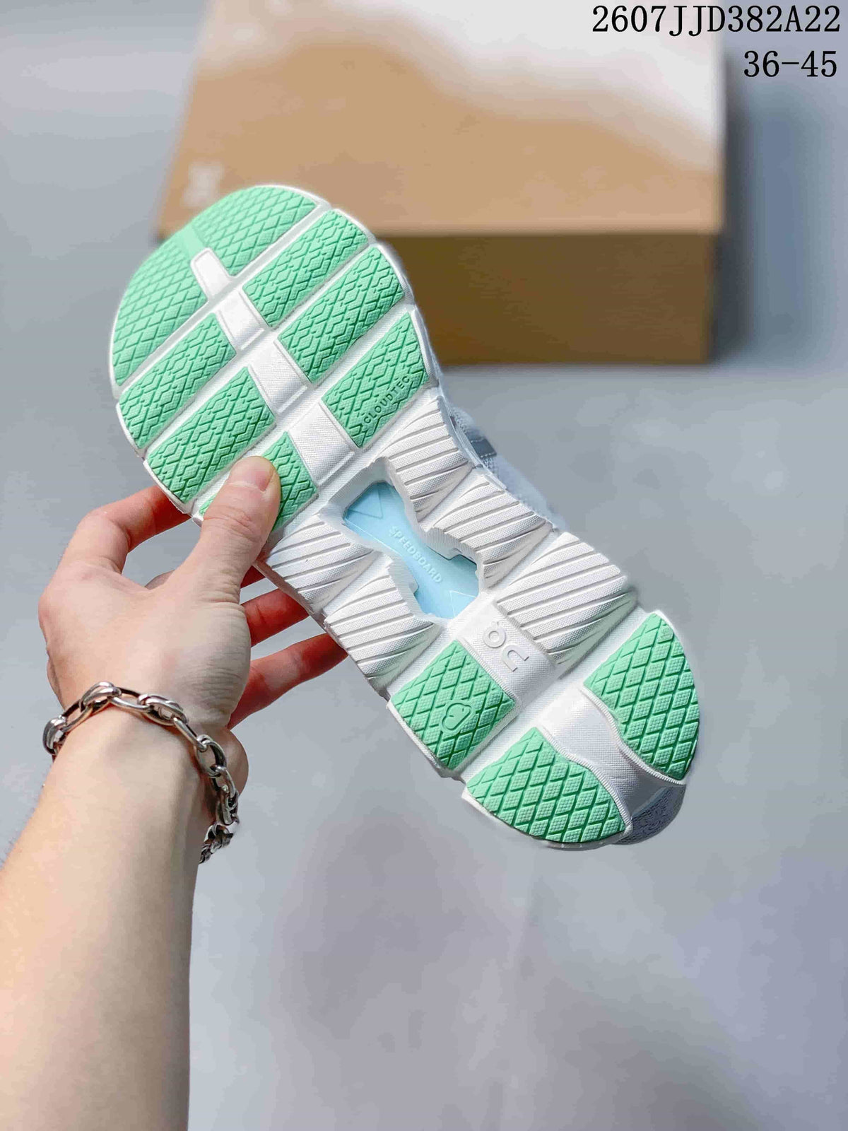 Bottom view of the sneaker showing the segmented white outsole, green traction sections and CloudTec branding.