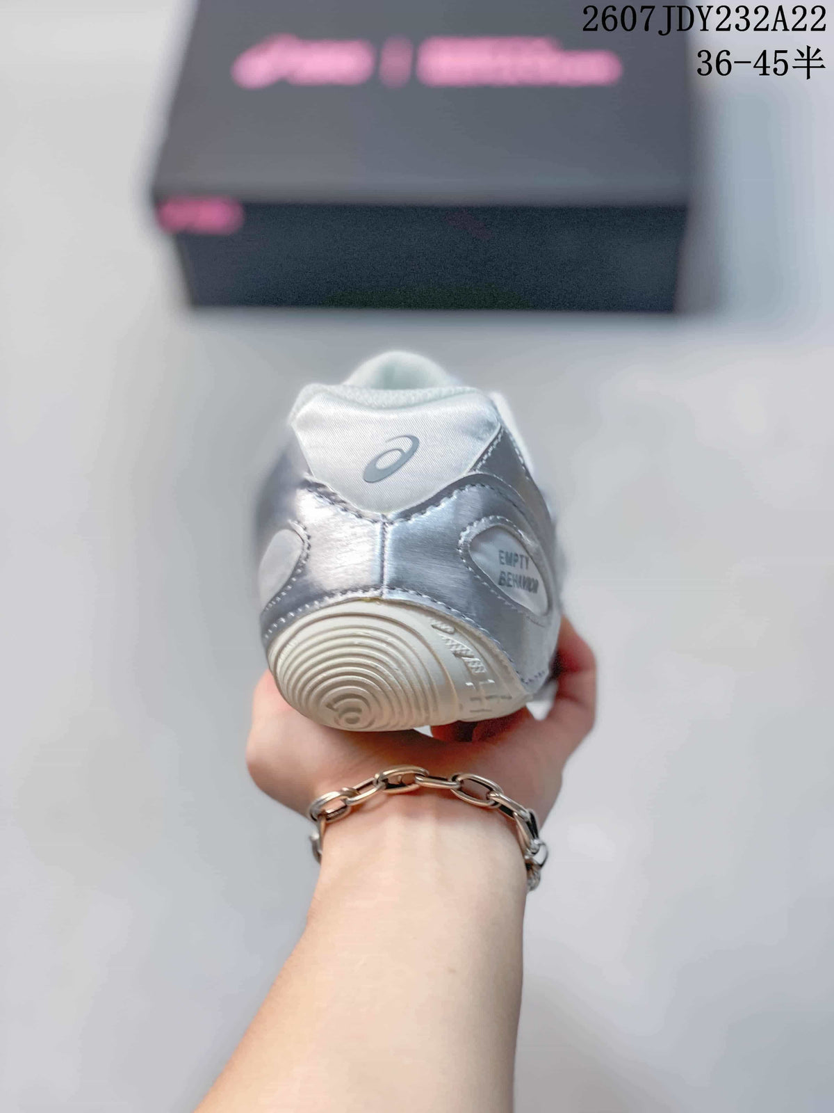 Rear view of the silver and white sneaker showing the padded heel, ASICS branding, and rounded outsole tread.