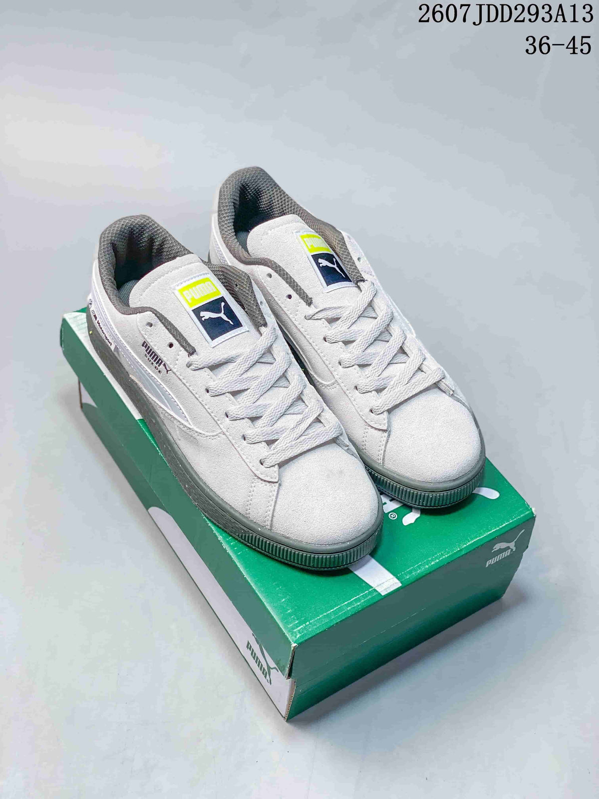 Pair of white and gray PUMA BMW MMS Suede XL sneakers displayed on a green shoebox; image text shows style code 2607JDD293A13 and size range 36–45.