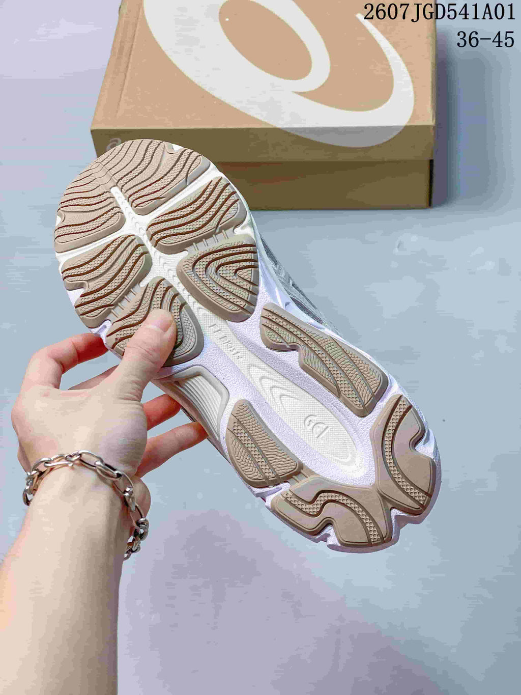 Close-up of the patterned outsole on a white and silver ASICS sneaker