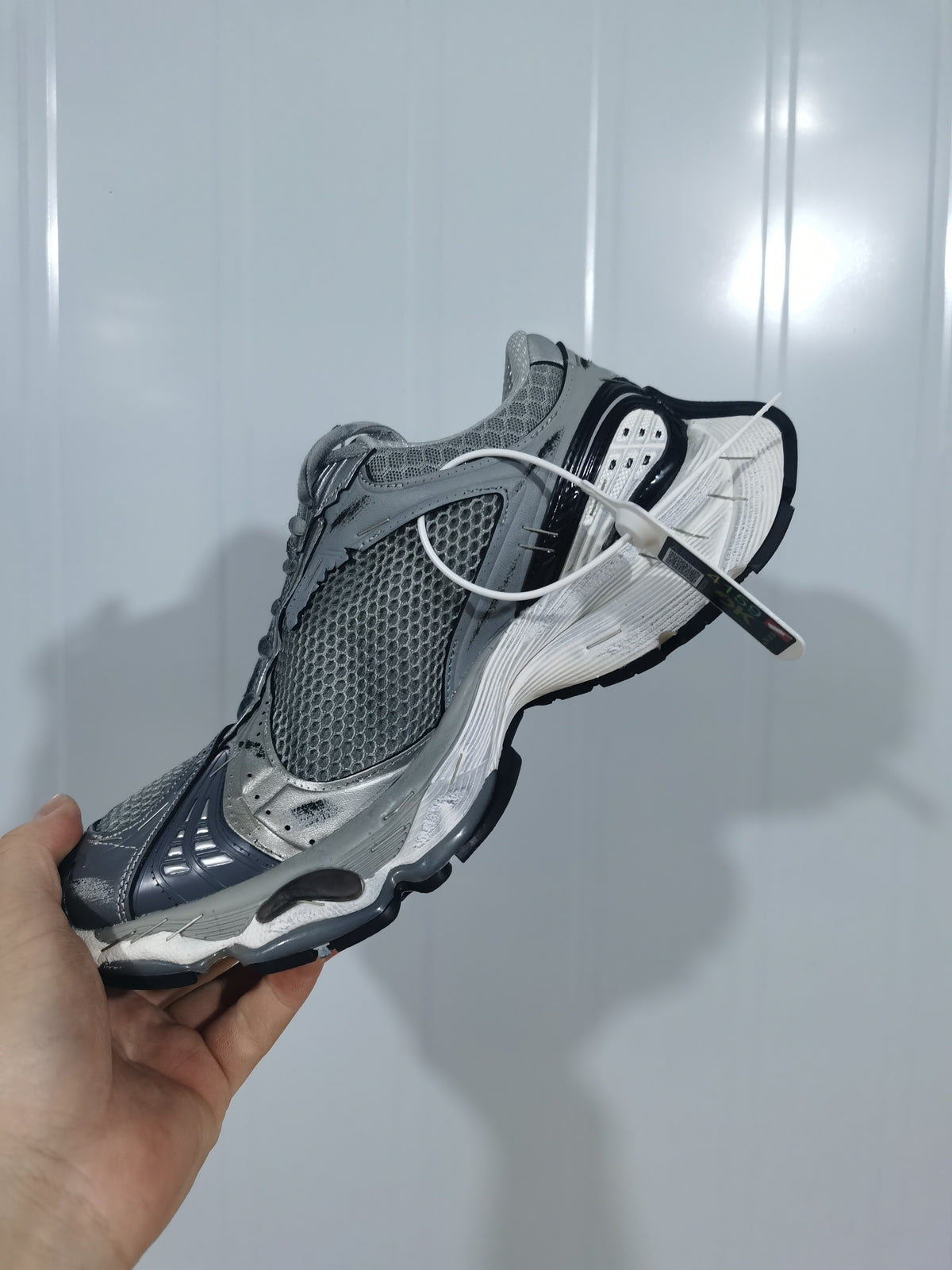 Close angled view of the sneaker showing the mesh panels, layered overlays, white midsole and black outsole.