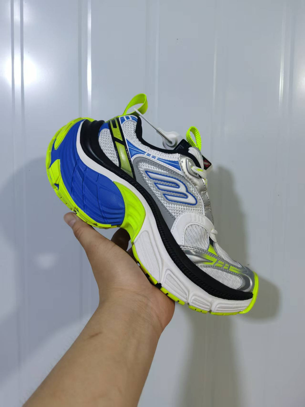 Rear three-quarter view highlighting the blue heel and neon green outsole.