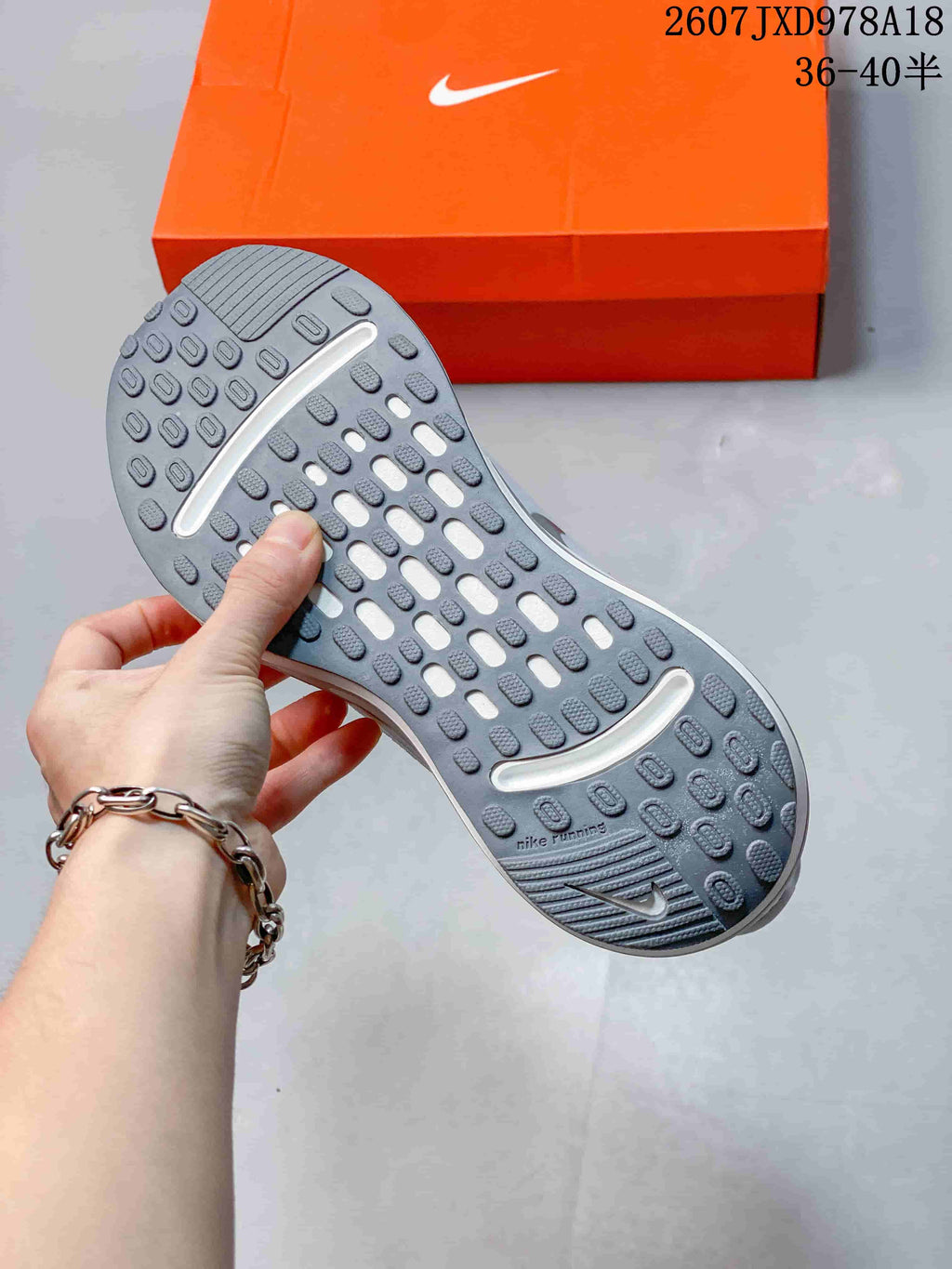 Close view of the gray rubber outsole with segmented traction pods and open channels, shown above an orange Nike shoebox.