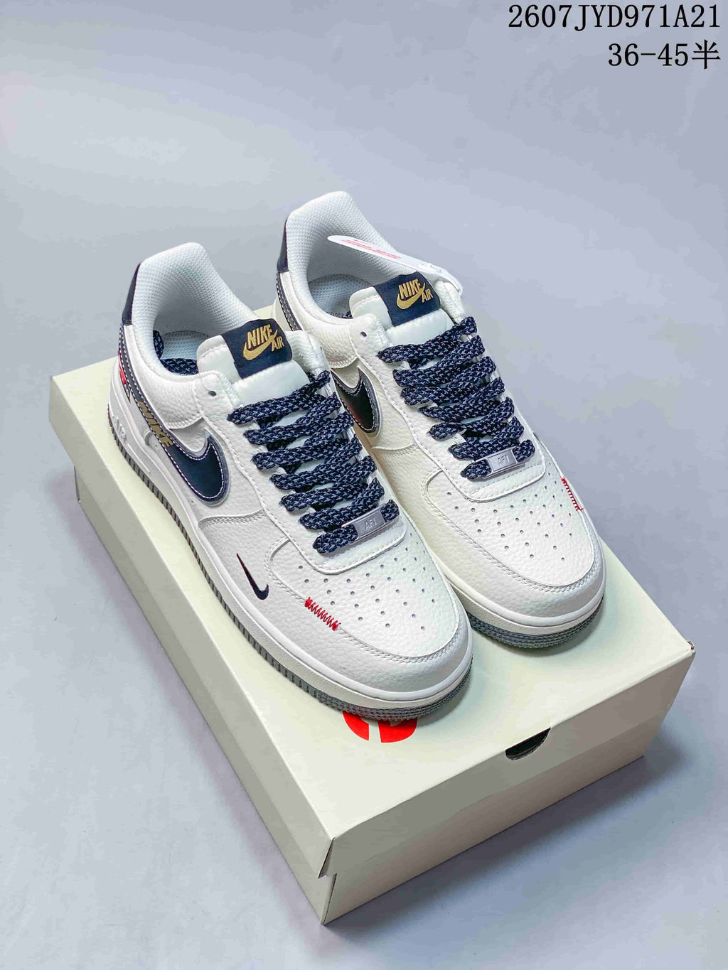 Pair of white Nike Air Force 1 '07 low-top sneakers with navy accents and patterned laces displayed on a shoebox; image text shows 36–45.5.