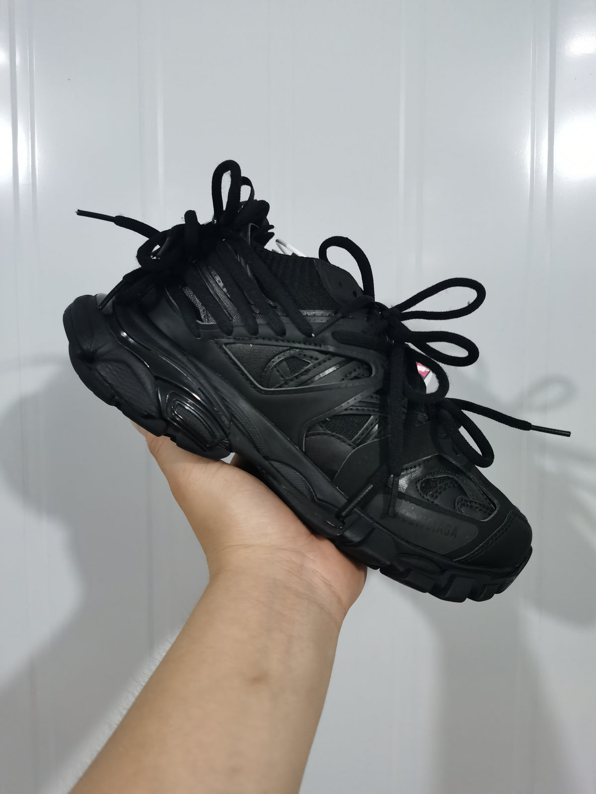 Black sneaker shown from the opposite side, highlighting the layered upper, extended laces, and textured sole.