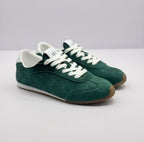 Pair of green Alo sneakers shown from a front three-quarter angle with white laces and brown toe edges.